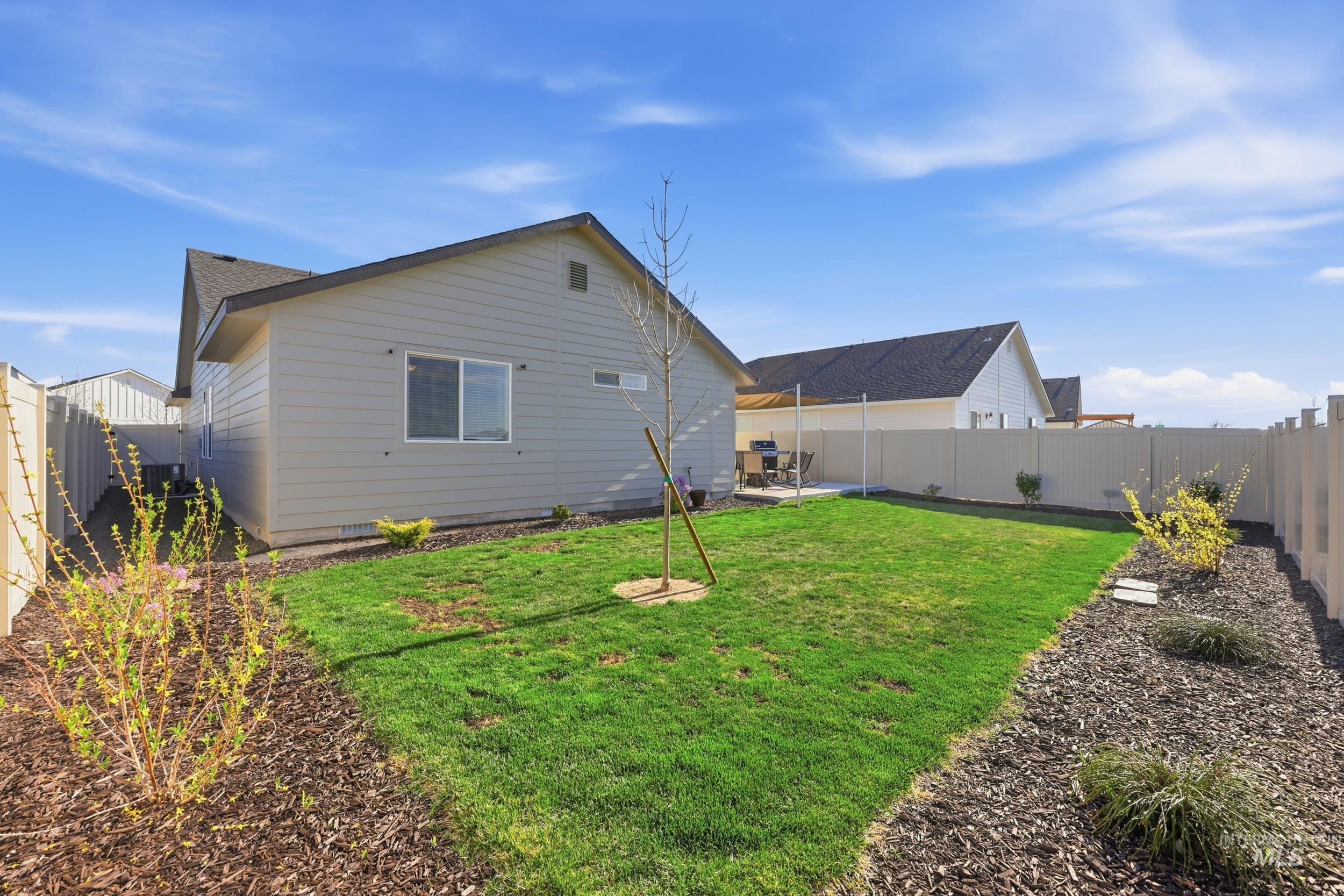 3697 W Lane Meridian, ID 83642 - Photo 36 of 44 Rear view of house featuring a fenced backyard and a patio. Drip system on plants, new bark, and new large tree!