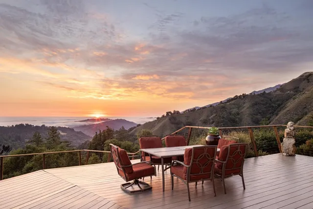 a view of a roof deck with table and chairs with wooden floor and mountain view