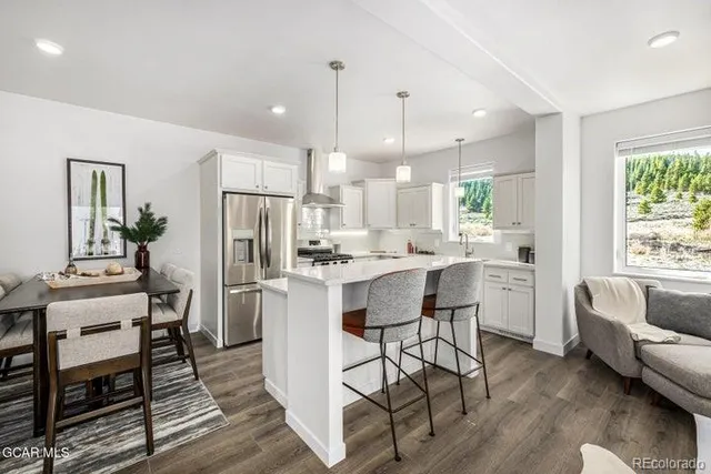 a kitchen with kitchen island a dining table chairs stainless steel appliances and cabinets