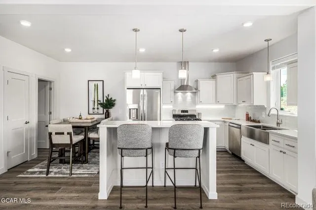 a kitchen with stainless steel appliances granite countertop wooden floor dining table and chairs