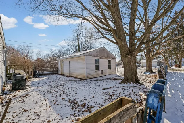 a backyard of a house with large trees and wooden fence