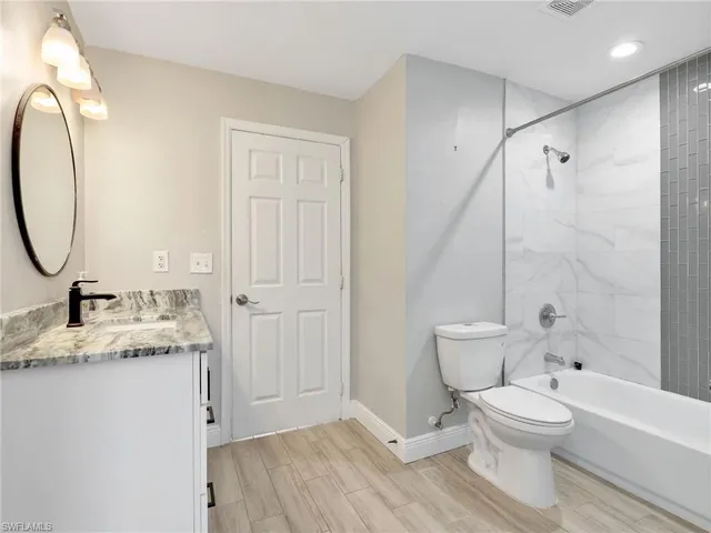 a bathroom with a granite countertop sink toilet a mirror and shower