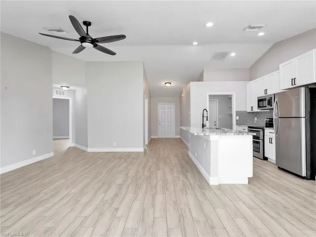 a view of a kitchen with refrigerator and wooden floor