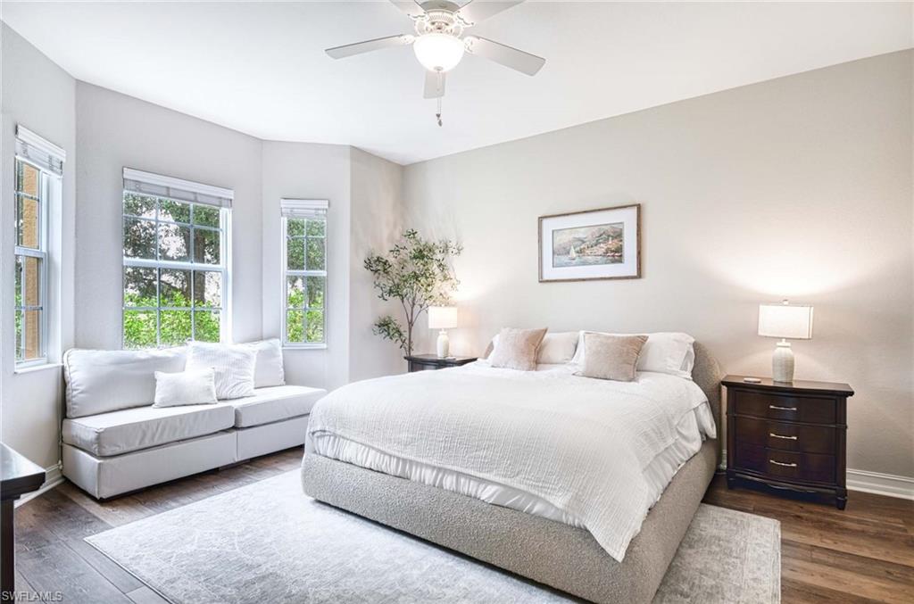 8649 Champions Point, Unit 1201 Naples, FL 34113 - Photo 12 of 23 Large primary bedroom en suite with wood grain luxury vinyl floor, lighted ceiling fan