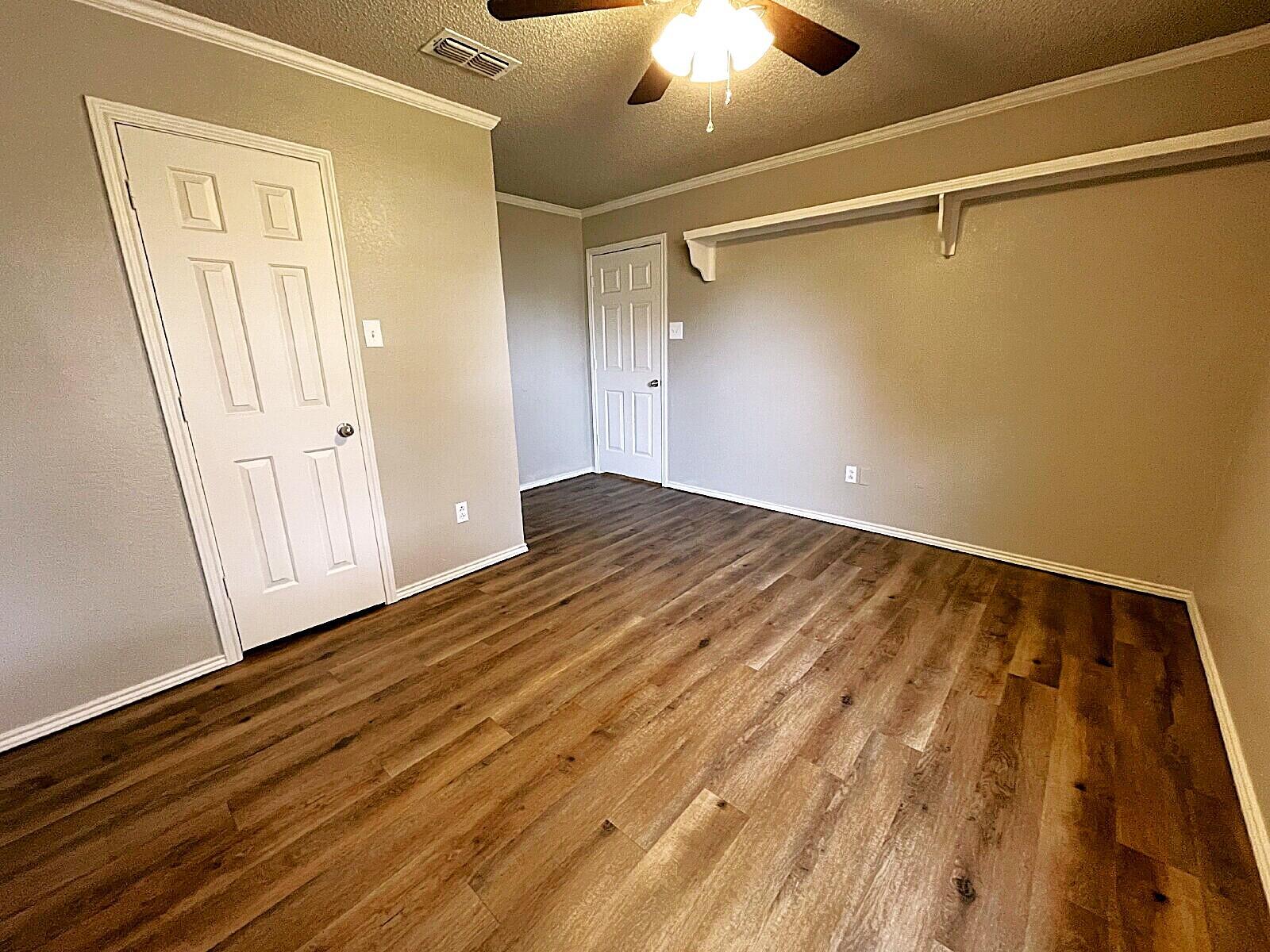 6328 10th Street Lubbock, TX 79416 - Photo 14 of 25 a view of empty room with wooden floor and fan