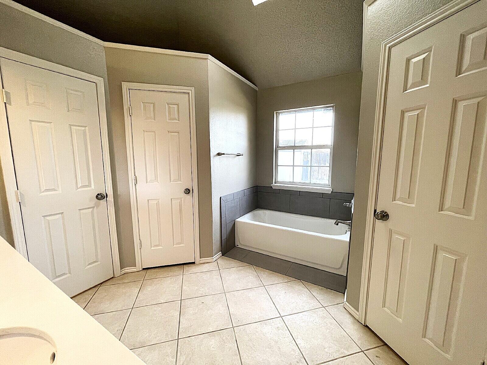 6328 10th Street Lubbock, TX 79416 - Photo 18 of 25 a bathroom with a bathtub and a shower