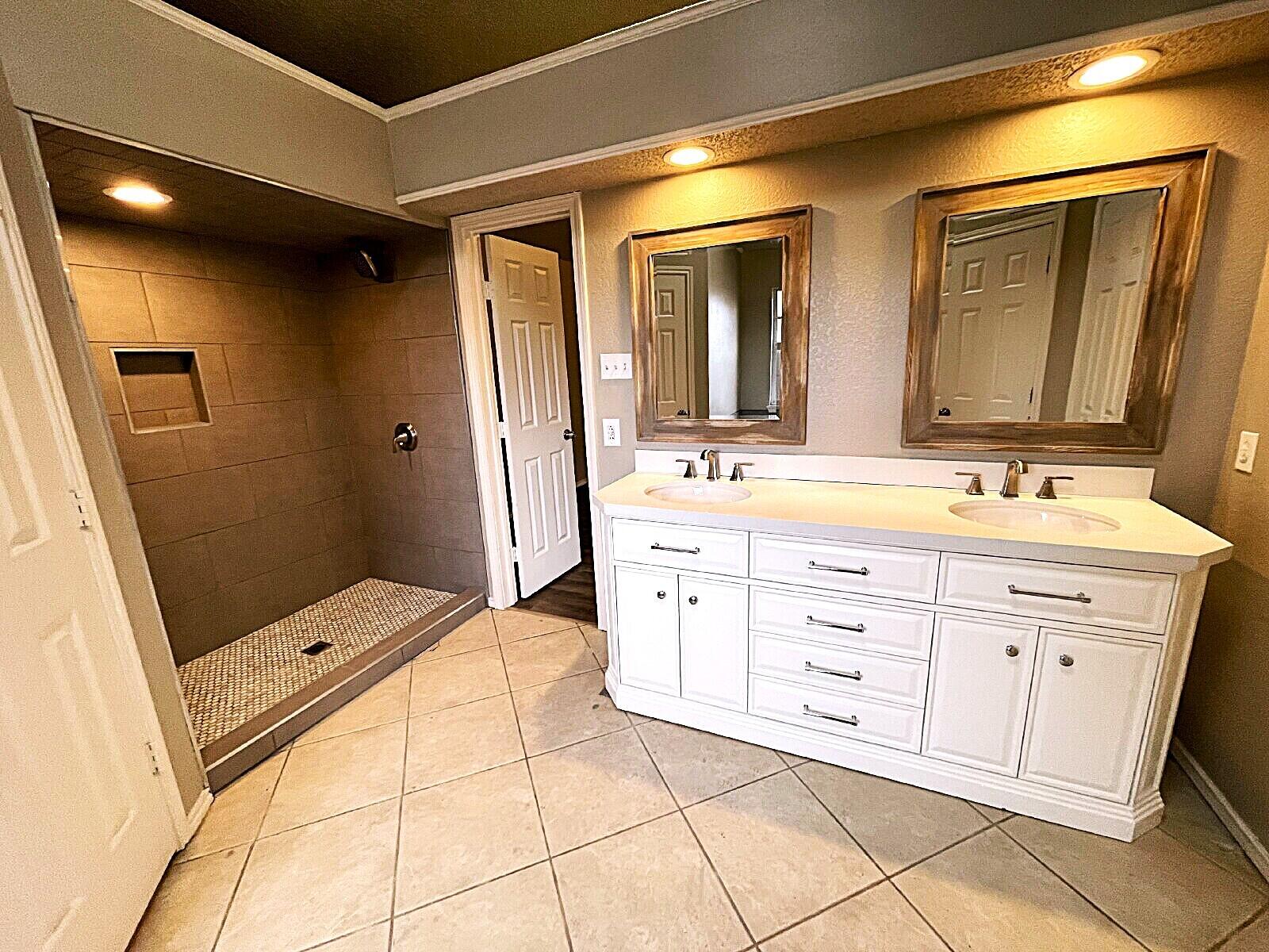 6328 10th Street Lubbock, TX 79416 - Photo 19 of 25 a spacious bathroom with a double vanity sink a mirror and a shower