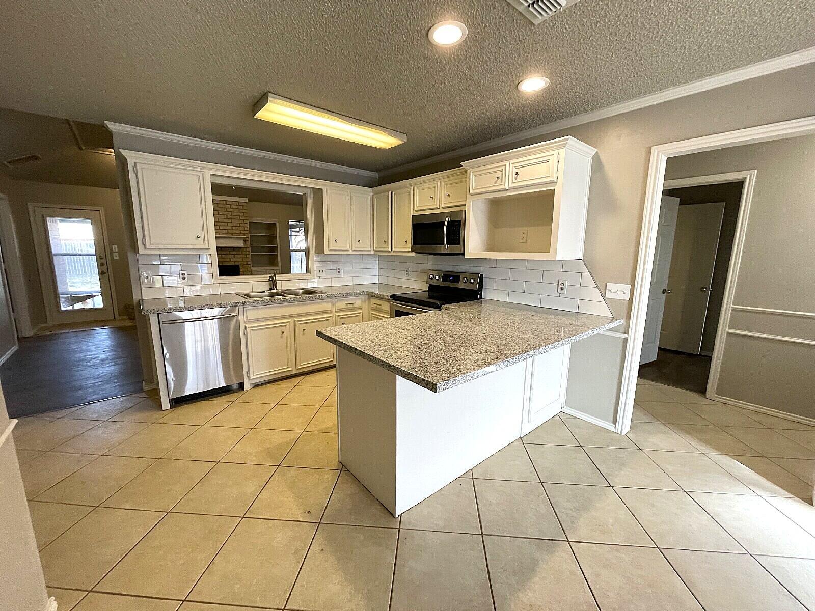 6328 10th Street Lubbock, TX 79416 - Photo 4 of 25 a kitchen with stainless steel appliances granite countertop a sink and a stove top oven