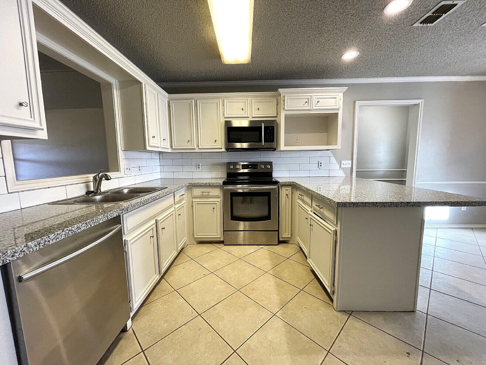 6328 10th Street Lubbock, TX 79416 - Photo 5 of 25 a kitchen with a sink a stove top oven and cabinets