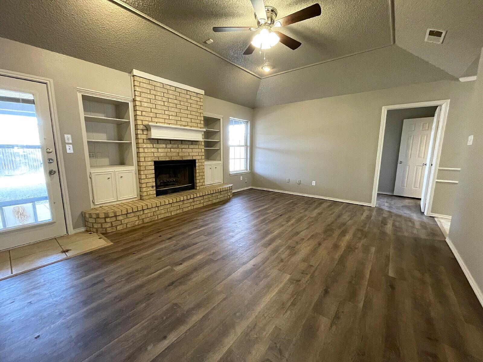 6328 10th Street Lubbock, TX 79416 - Photo 6 of 25 a view of an empty room with wooden floor fireplace and a window