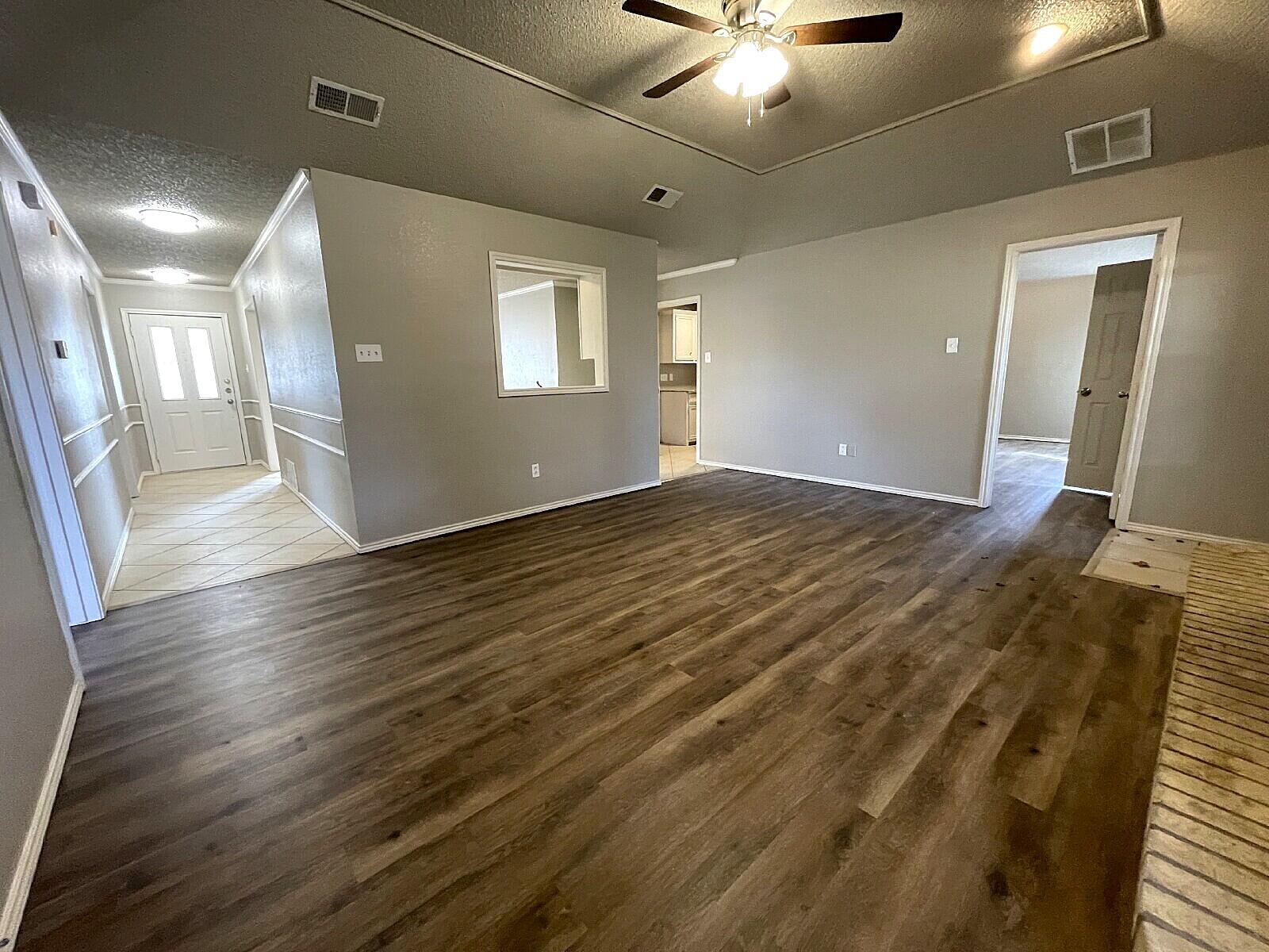 6328 10th Street Lubbock, TX 79416 - Photo 7 of 25 a view of an empty room with wooden floor and a ceiling fan