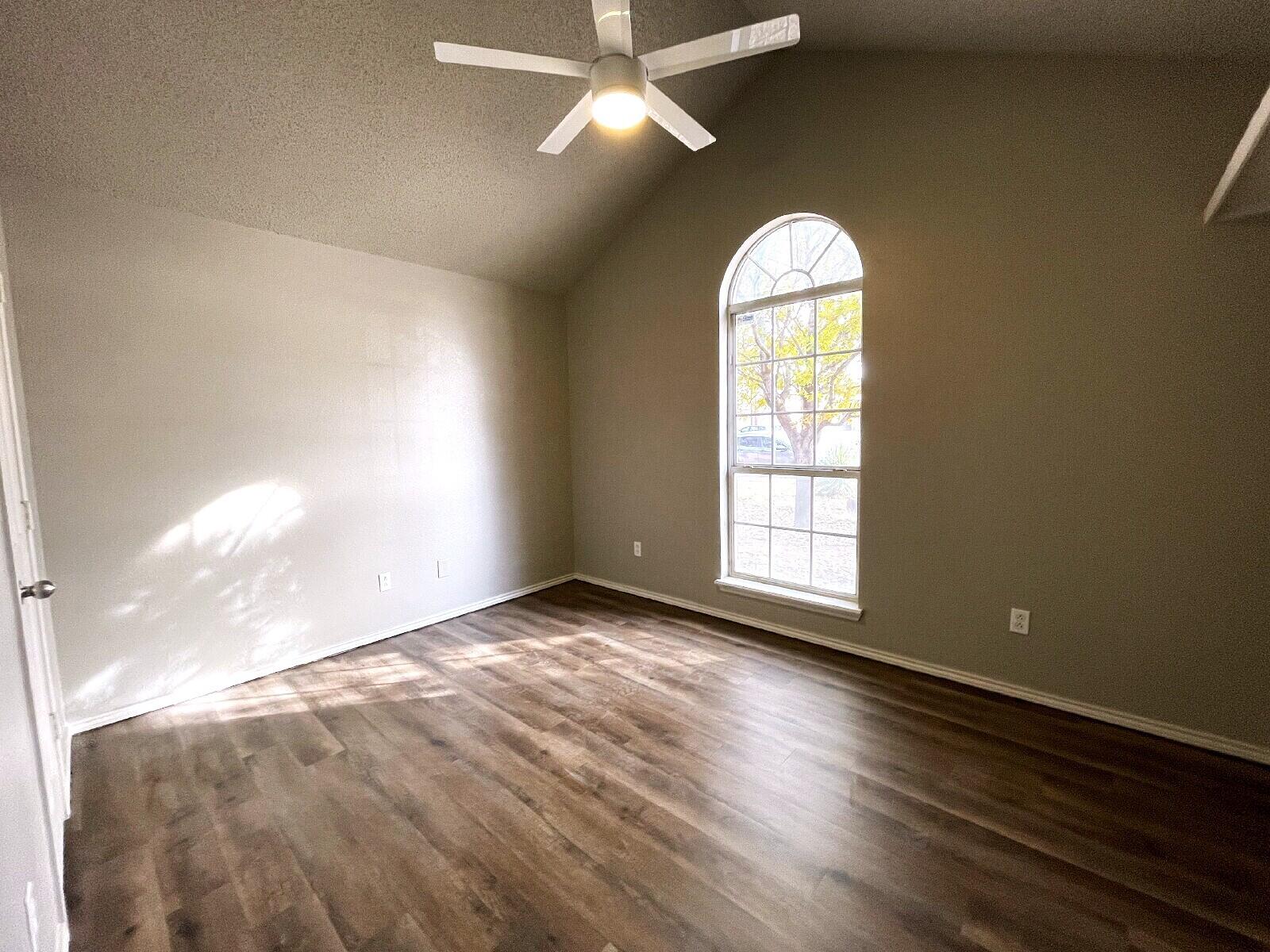 6328 10th Street Lubbock, TX 79416 - Photo 8 of 25 an empty room with wooden floor chandelier fan and windows