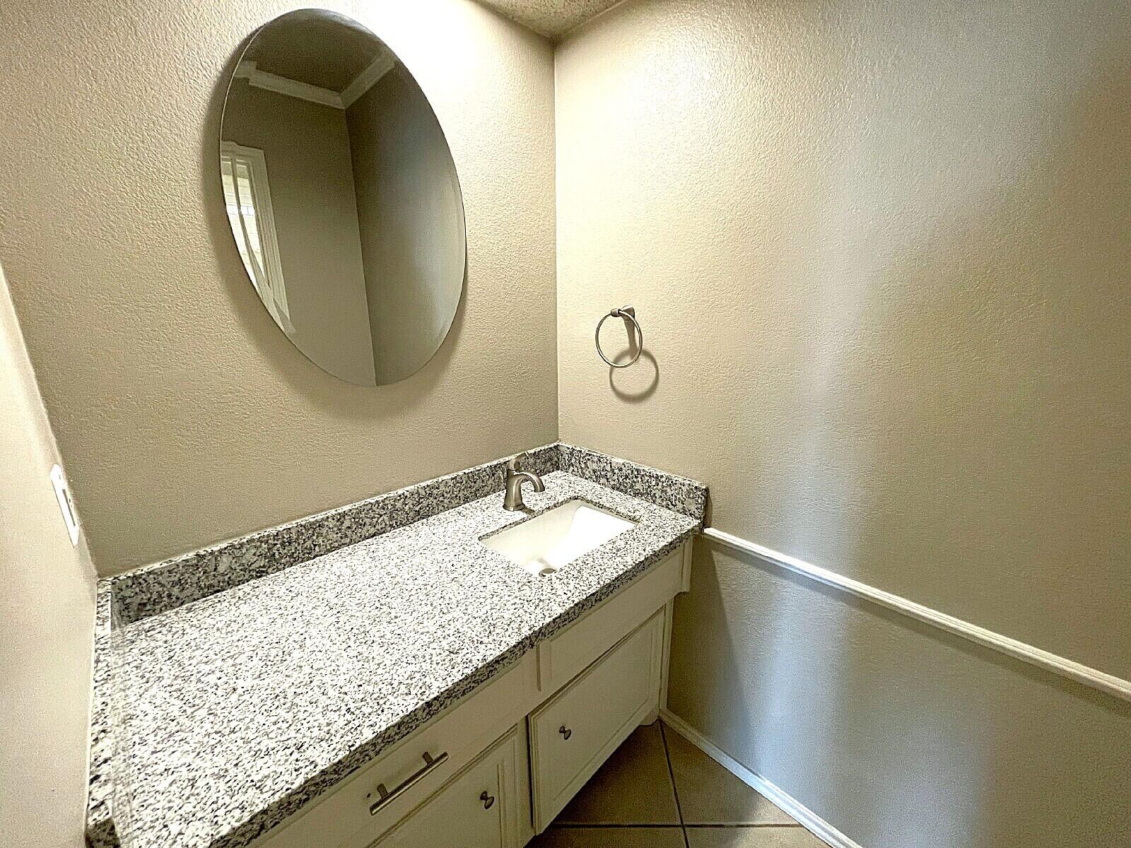 6328 10th Street Lubbock, TX 79416 - Photo 10 of 25 a bathroom with a granite countertop sink and a mirror