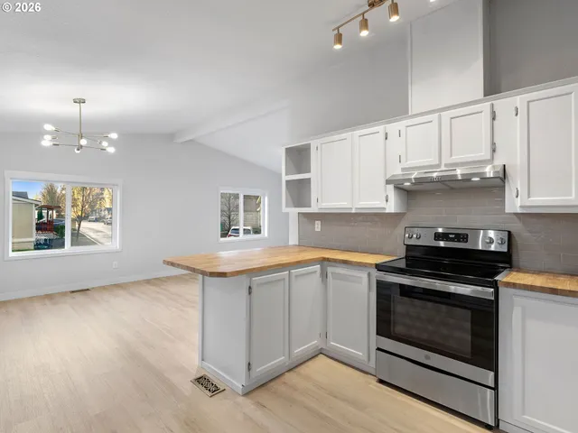 a kitchen with granite countertop a stove a sink and dishwasher with white cabinets