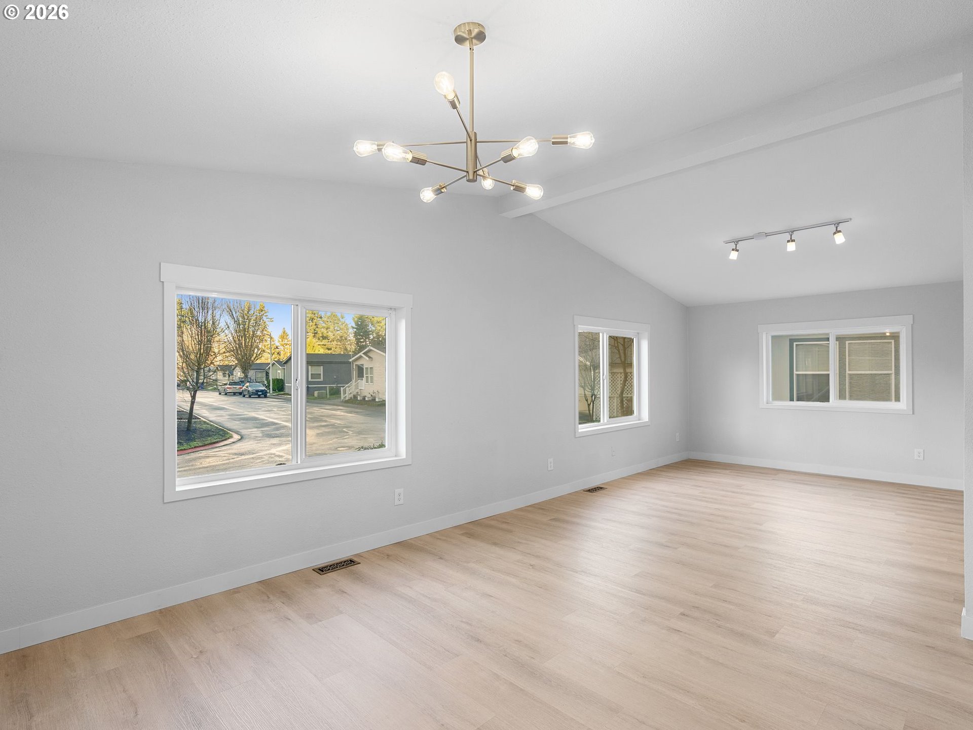 15768 Southeast Powell Boulevard, Unit 12 Portland, OR 97236 - Photo 7 of 31 an empty room with wooden floor chandelier and windows