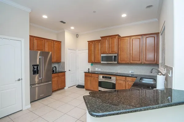 a kitchen with stainless steel appliances granite countertop a stove a sink a microwave a refrigerator and cabinets