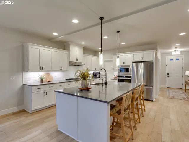 a kitchen with stainless steel appliances granite countertop a sink a stove a refrigerator and island