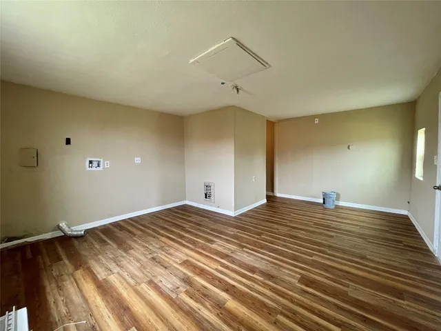 a view of an empty room with a window and wooden floor