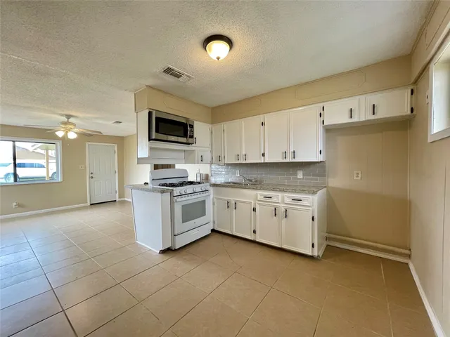 a kitchen with granite countertop a stove top oven sink and cabinets