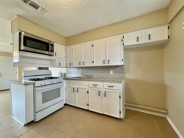 a kitchen with stainless steel appliances white cabinets and a stove top oven