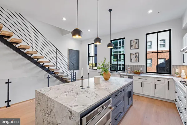 a kitchen with stainless steel appliances kitchen island granite countertop a dining table chairs and a refrigerator