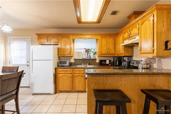 a kitchen with stainless steel appliances granite countertop a refrigerator a stove a sink dishwasher and white cabinets with wooden floor