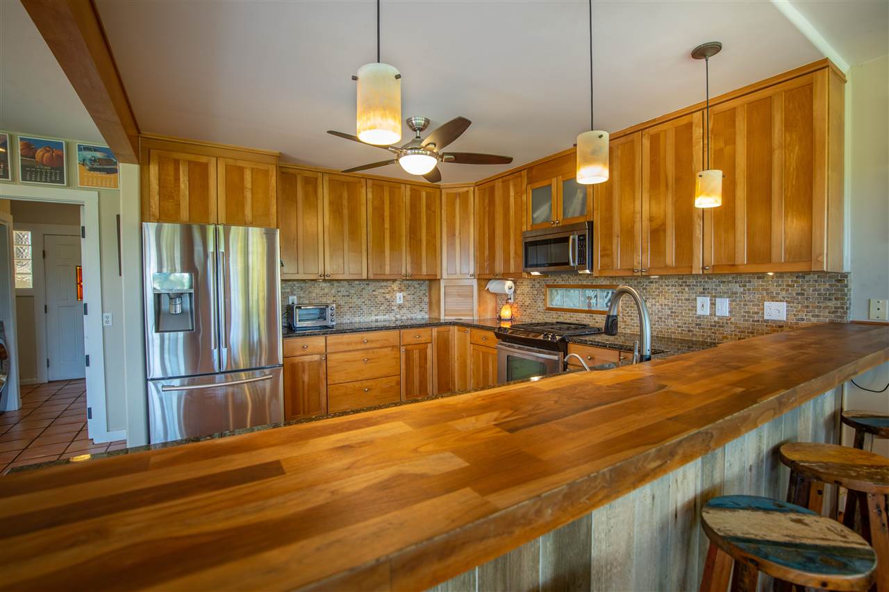 475 Haumana Road Haiku, HI 96708 - Photo 8 of 30 a kitchen with stainless steel appliances wooden cabinets a sink and a refrigerator