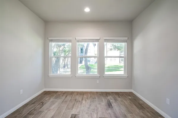 an empty room with wooden floor and windows