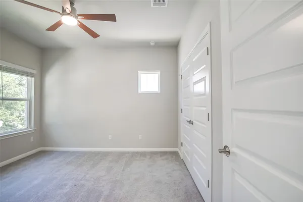 an empty room with windows and fan