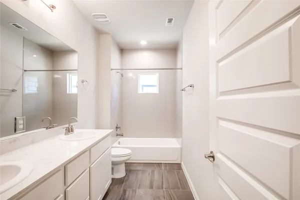 a bathroom with a granite countertop sink a toilet and shower