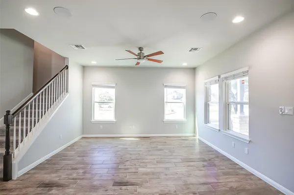 an empty room with wooden floor and windows