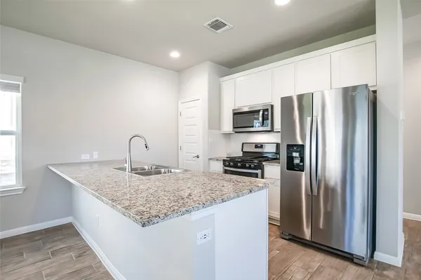 a kitchen with granite countertop a refrigerator and a sink