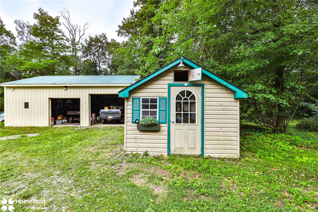 3795 Rhoades Road Kempton, PA 19529 - Photo 38 of 42 A quaint detached shed with charming shutters sits beside a spacious garage, offering ample storage and utility.