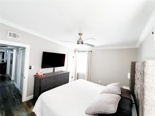 a bedroom with a bed and a flat tv screen on wall