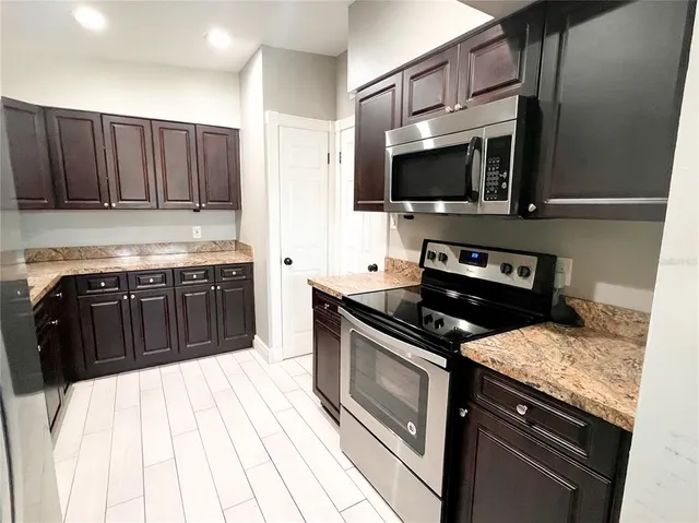 a kitchen with stainless steel appliances granite countertop a stove a sink and a microwave