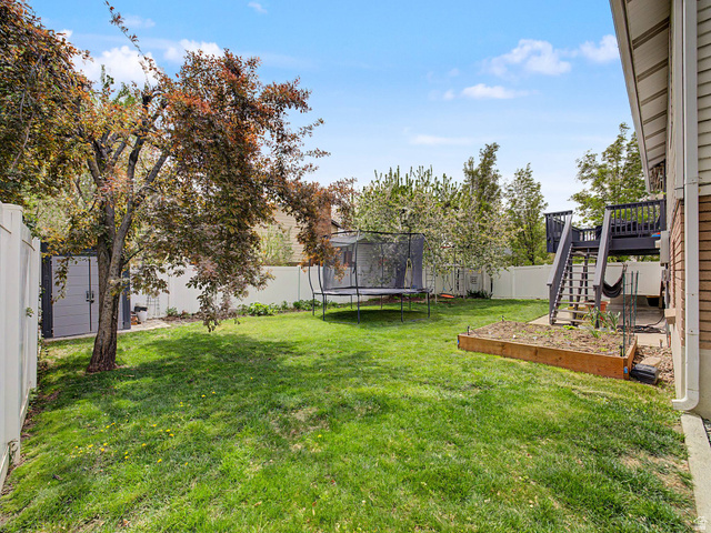 523 Mountain View Road Centerville, UT 84014 - Photo 24 of 33 Fenced backyard featuring a trampoline, a vegetable garden, and a deck
