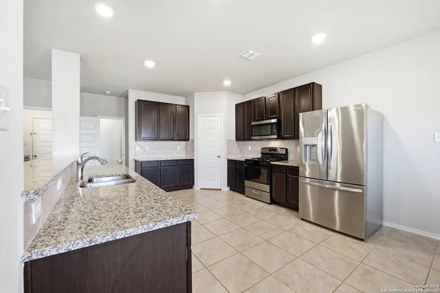 a kitchen with stainless steel appliances granite countertop a refrigerator a stove a sink and a microwave