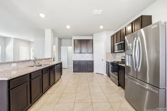 a large kitchen with a large counter top stainless steel appliances and cabinets