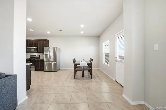 a kitchen with stainless steel appliances a refrigerator and a stove top oven with white cabinets
