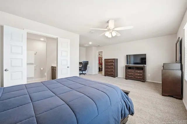 a spacious bedroom with a bed a chandelier and a flat screen tv