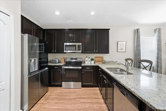 a kitchen with stainless steel appliances granite countertop a sink stove refrigerator and cabinets