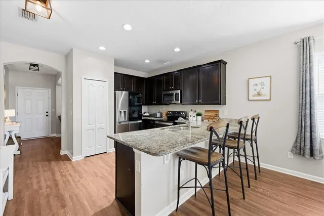 a kitchen with stainless steel appliances granite countertop a stove top oven a sink and a refrigerator