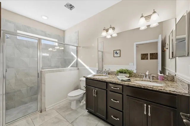 a bathroom with a double vanity sink toilet mirror and shower
