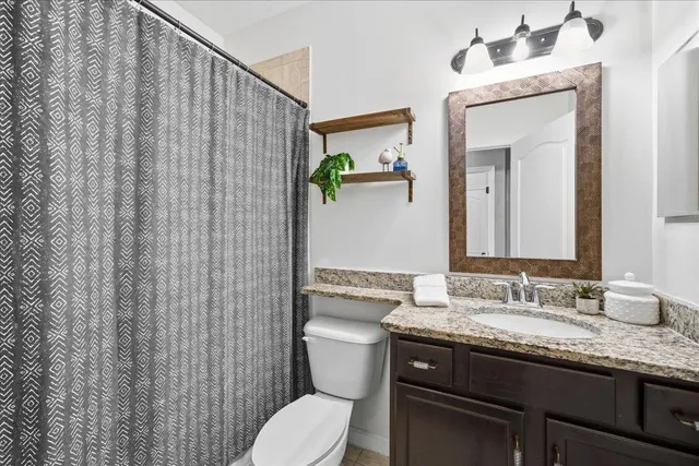 a bathroom with a granite countertop toilet sink and mirror