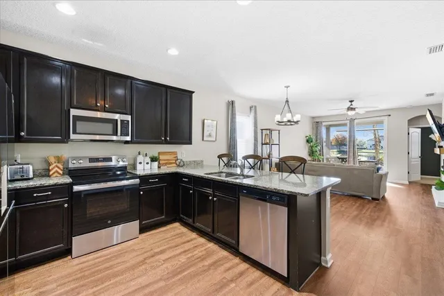 a kitchen with stainless steel appliances granite countertop a sink stove and wooden cabinets