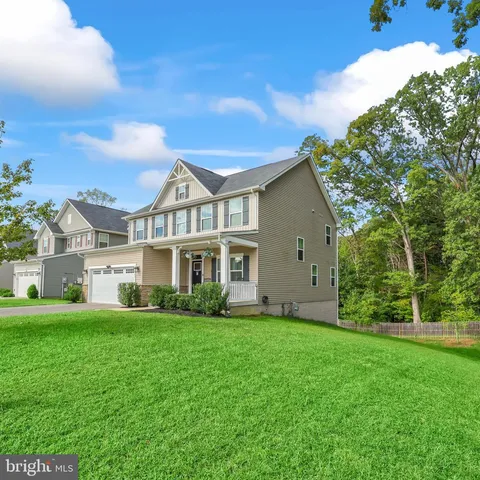 a view of a house next to a big yard and large trees