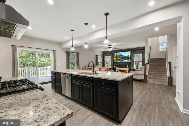 a kitchen with stainless steel appliances granite countertop a sink a stove and a wooden floor