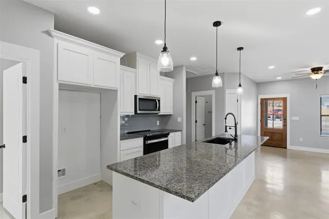 a kitchen with stainless steel appliances granite countertop a sink a refrigerator and a counter top space