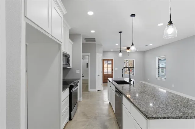 a kitchen with stainless steel appliances granite countertop a sink a counter top space cabinets and a chandelier