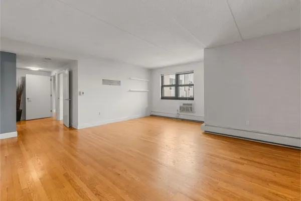 a view of empty room with wooden floor and window